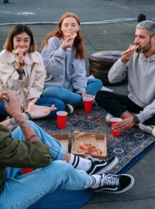 Un groupe d’ami en soirée, mangent une pizza et jouent à un jeu d’ambiance
